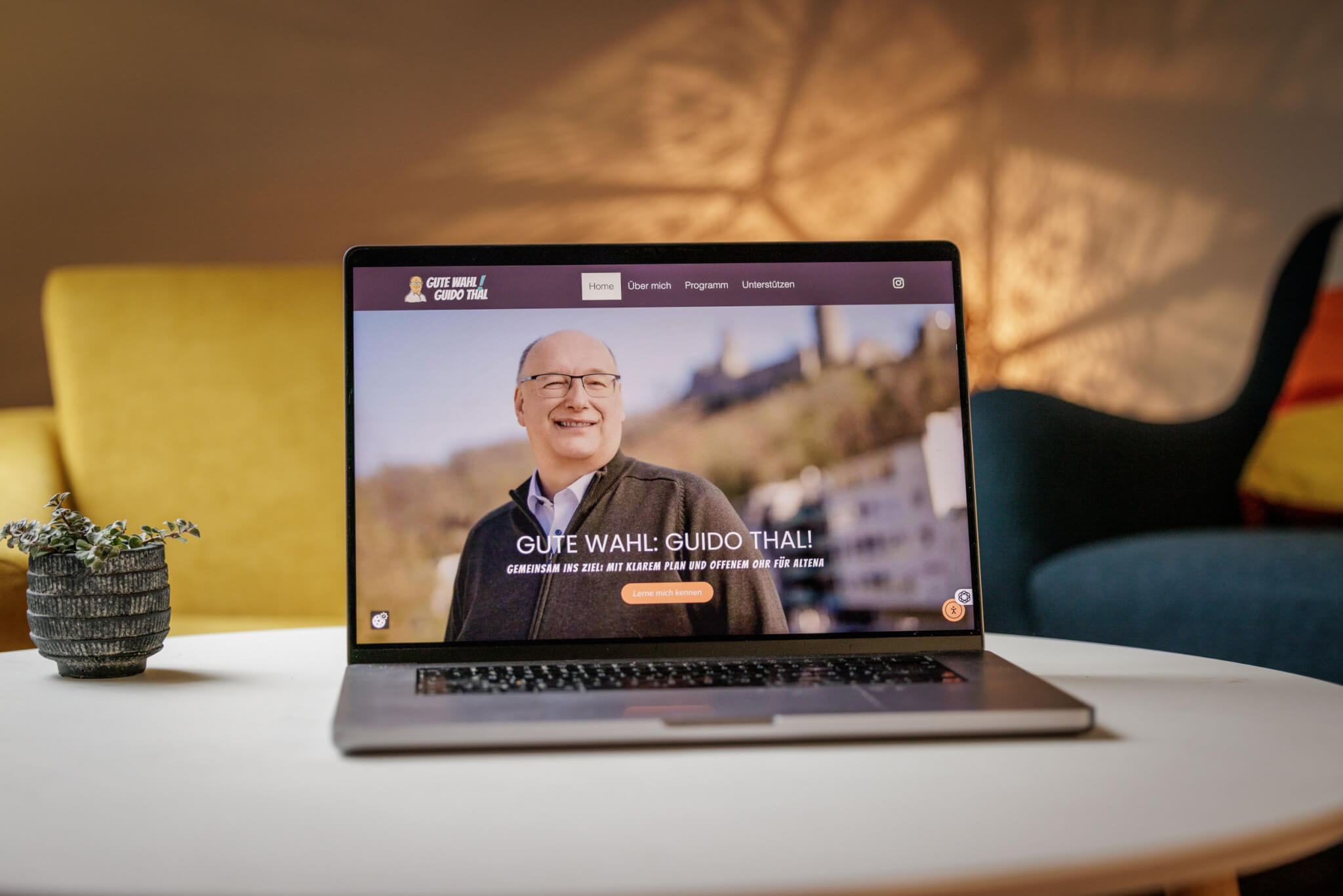 Auf einem Tisch steht ein Laptop. Auf dem Bildschirm ist eine Homepage für Bürgermeister Kandidaten Guido Thal aus Altena zu sehen.