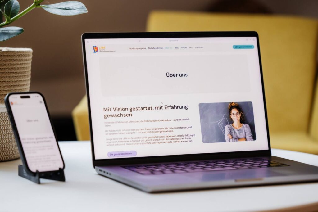 Macbook und Handy mit geöffneter Webseite auf einem Couchtisch